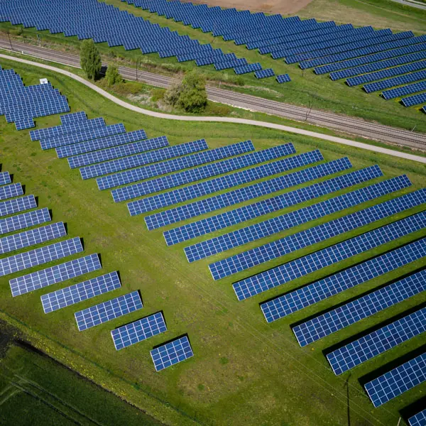 Rows of solar panels across green fields seen from above